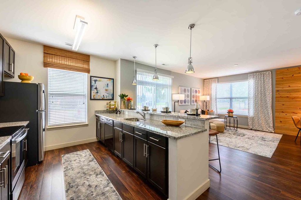 A modern kitchen with dark wood floors and stainless steel appliances.