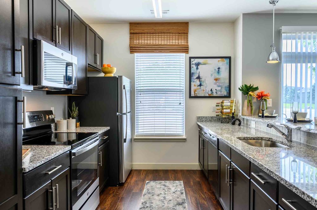 A kitchen with black cabinets and granite countertops.