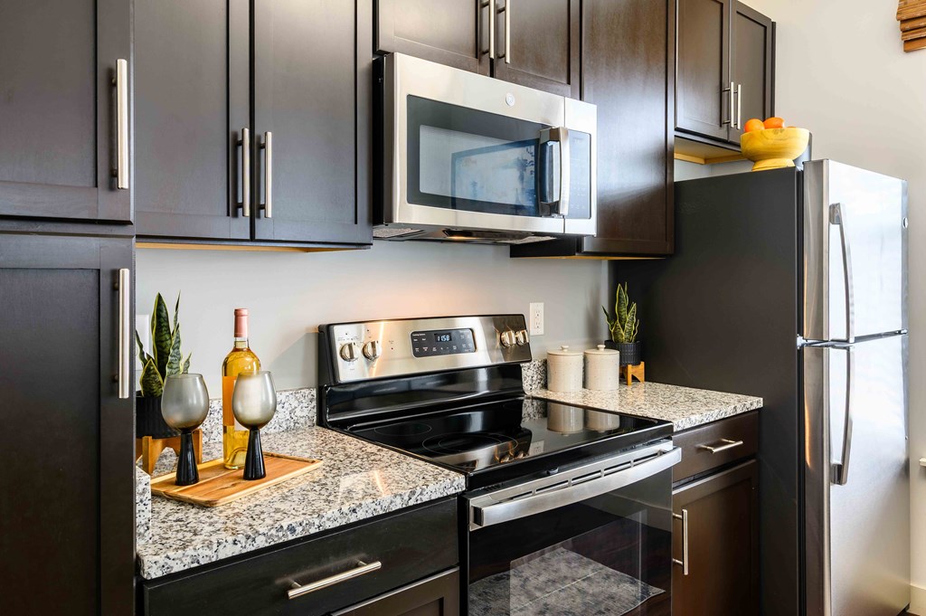 A modern kitchen with a black refrigerator, microwave, and stove.