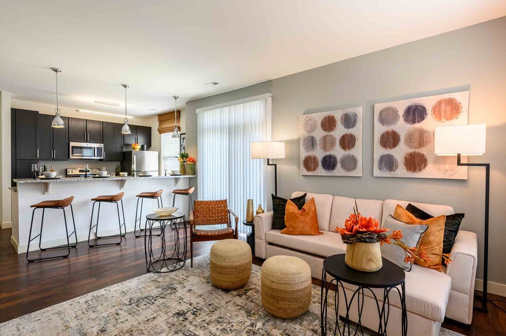 A modern living room with a kitchen area in the background.