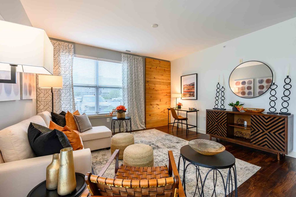 A living room with a white couch, a black coffee table, and a round mirror on the wall.