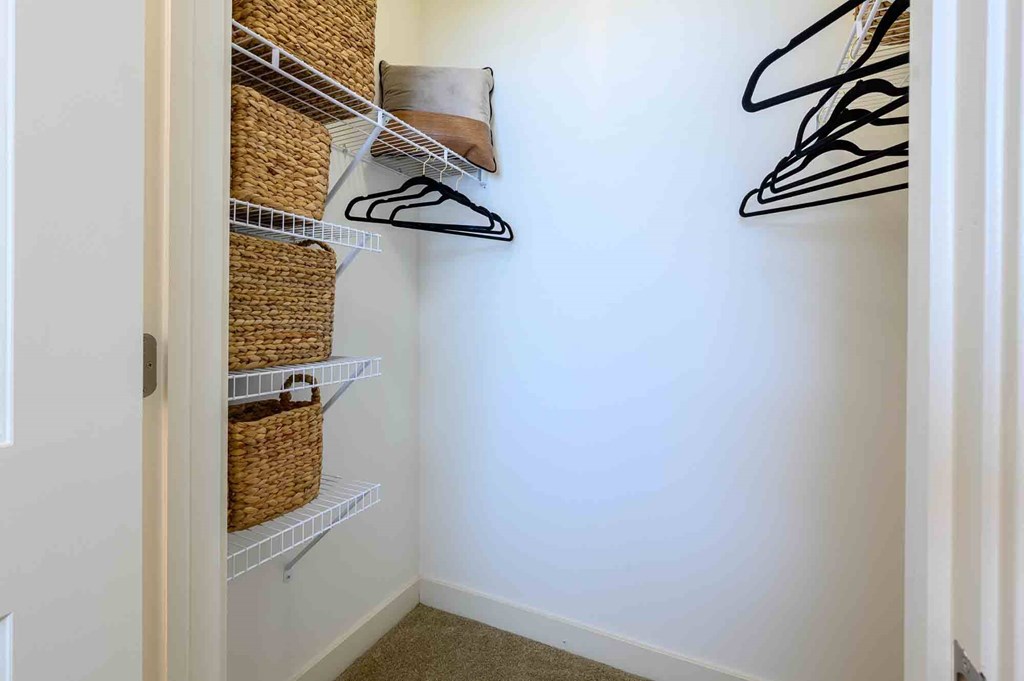 A white closet with a white door, a white shelf, and a white wall.