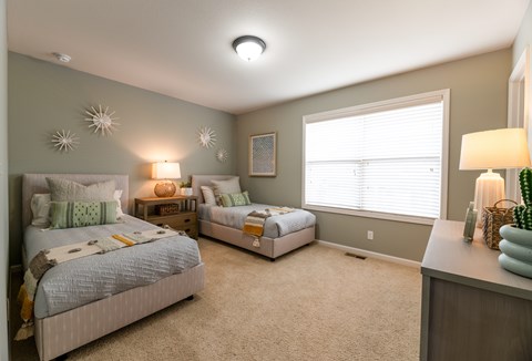 Guest bedroom with two beds and decorative accents at Prairie Pines Townhomes Apartments, Shawnee, 66226