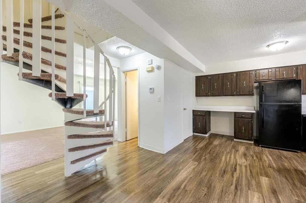 A kitchen area with a black fridge and wooden cabinets at Spring Creek Townhomes Apartments, Illinois 62702
