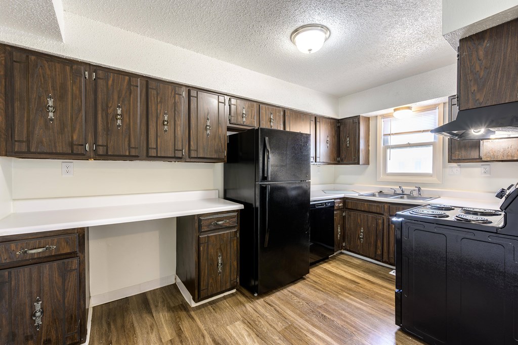 A kitchen with wooden cabinets and a black fridge at Spring Creek Townhomes Apartments, Springfield