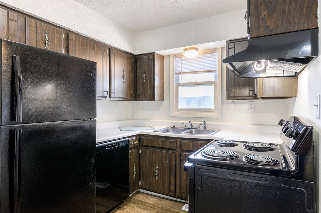 A black fridge and stove in a kitchen with wooden cabinets at Spring Creek Townhomes Apartments, Springfield 62702