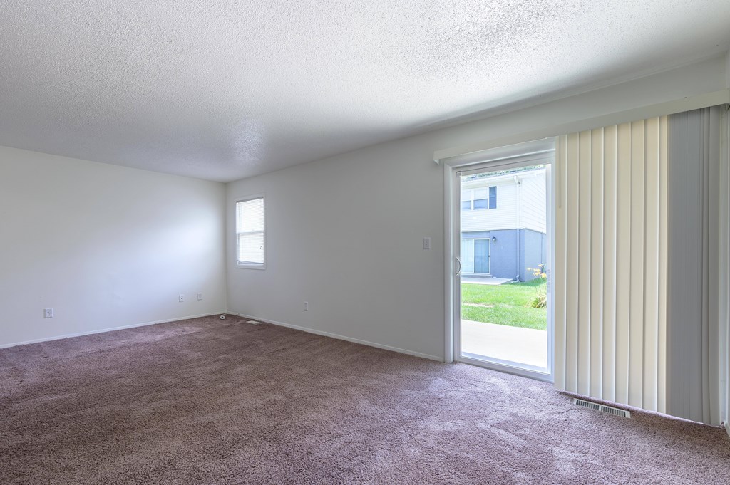 A room with a carpeted floor and a sliding glass door at Spring Creek Townhomes Apartments, Springfield, IL 62702