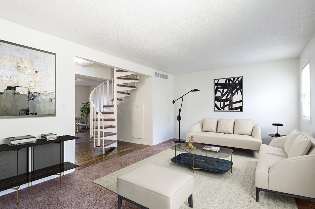 A living room with a white couch, a black coffee table, and a spiral staircase at Spring Creek Townhomes Apartments, Springfield, IL 62702