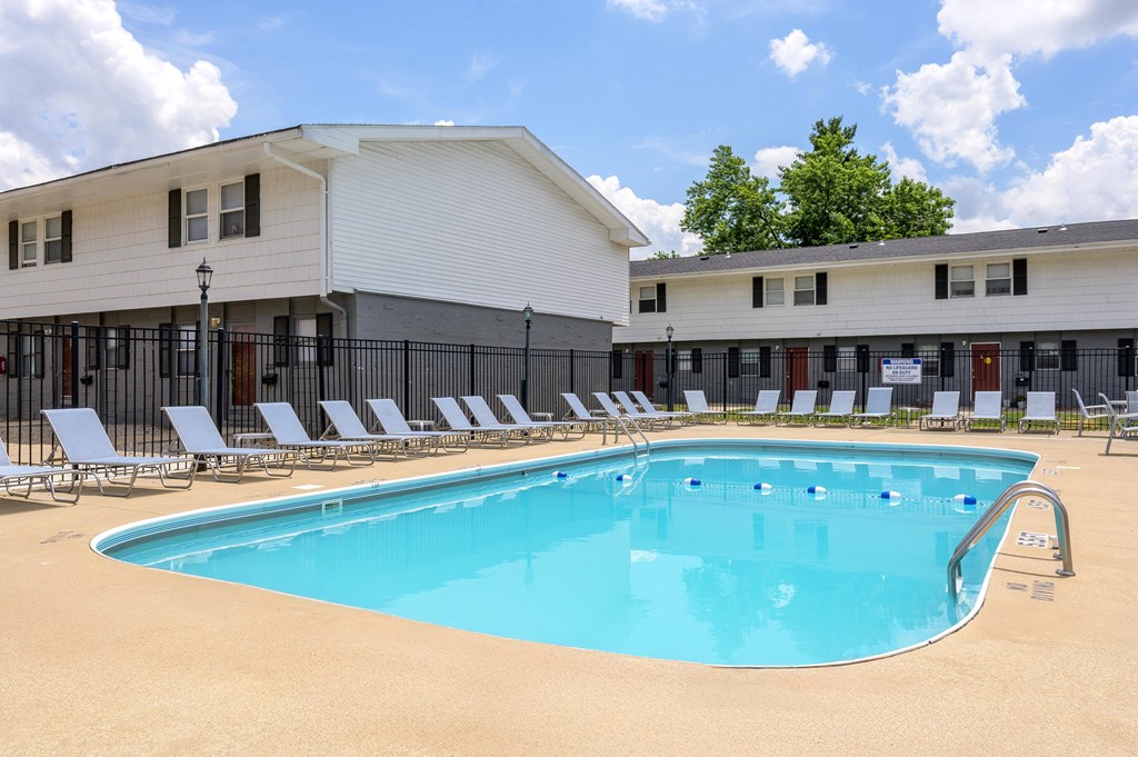 A large swimming pool with lounge chairs in front of a white building at Spring Creek Townhomes Apartments, Springfield, Illinois