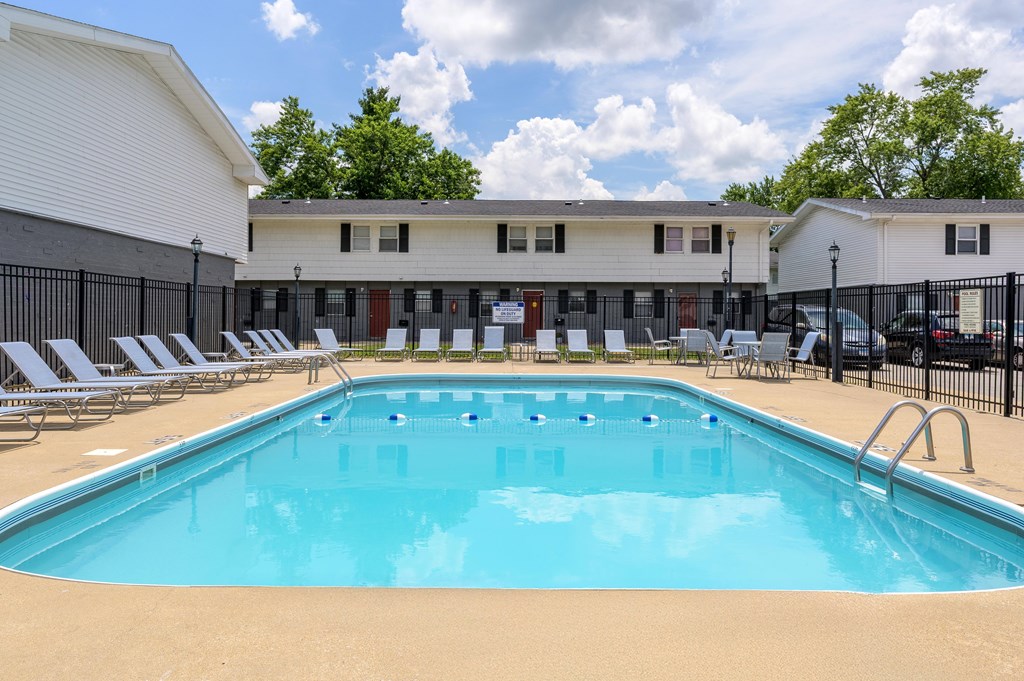 A large swimming pool in front of a building with lounge chairs around it at Spring Creek Townhomes Apartments, Springfield, IL