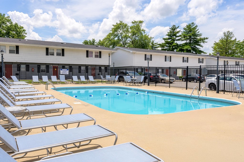 A pool surrounded by sun loungers and a building in the background at Spring Creek Townhomes Apartments, Illinois