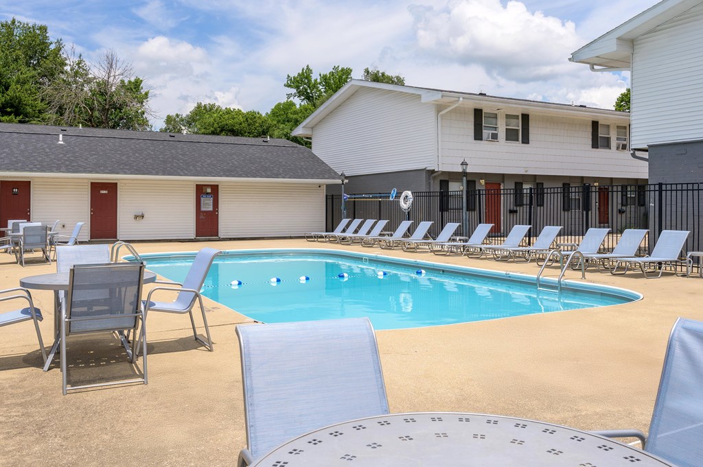 A pool with chairs around it and a building in the background at Spring Creek Townhomes Apartments, Springfield