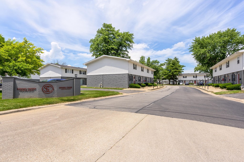 A street view of a residential area with houses and a sign that reads at Spring Creek Townhomes Apartments, Springfield, Illinois
