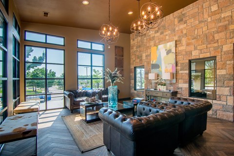 A living room with a black leather couch and a chandelier.