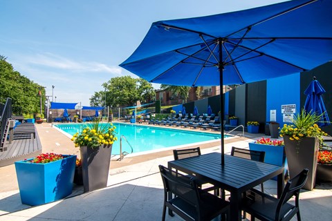 Outdoor pool deck with lounge seating and umbrellas at The Boulevard Apartments, Roeland Park, KS