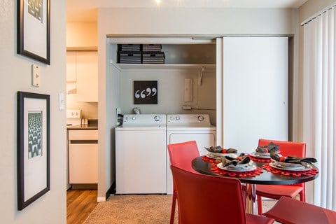 A kitchen with a table and chairs in the foreground and a washing machine in the background.