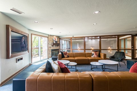 A living room with a brown leather couch and a television on the wall.