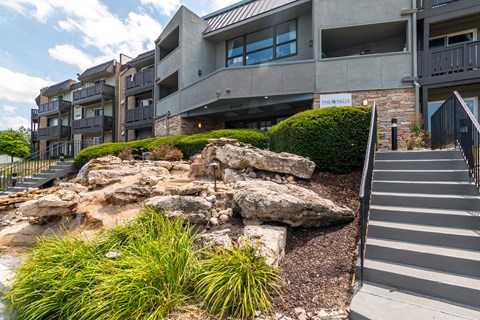 Exterior stairway with natural rock landscaping and greenery at The Falls Apartments, Mission, Kansas