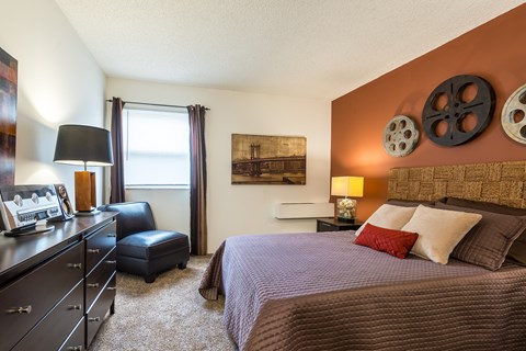 A bedroom with a bed, dresser, and window.
