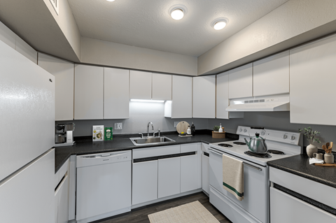 A kitchen with white cabinets and black countertops.