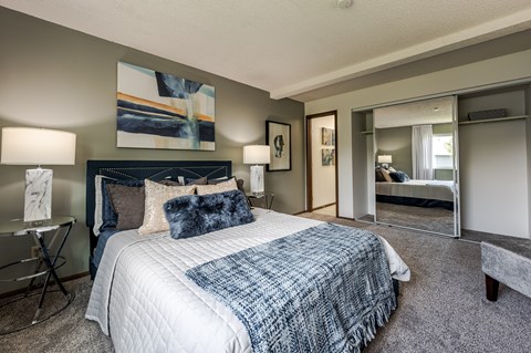 Master bedroom with mirrored closet and navy accents at Candles Apartments, Springfield, IL 62704