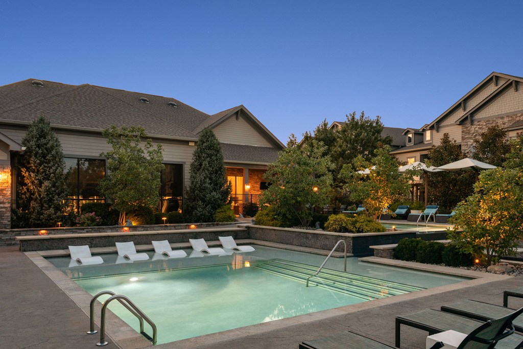 A pool surrounded by lounge chairs and trees.