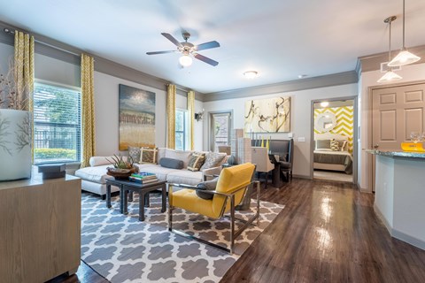 A living room with a yellow chair and a grey and white patterned rug.