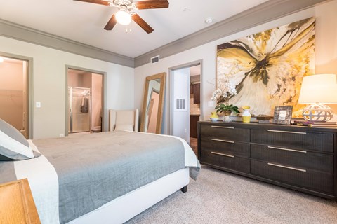 A bedroom with a bed, dresser, and a ceiling fan at Waterstone at Cinco Ranch Apartments, Katy Texas