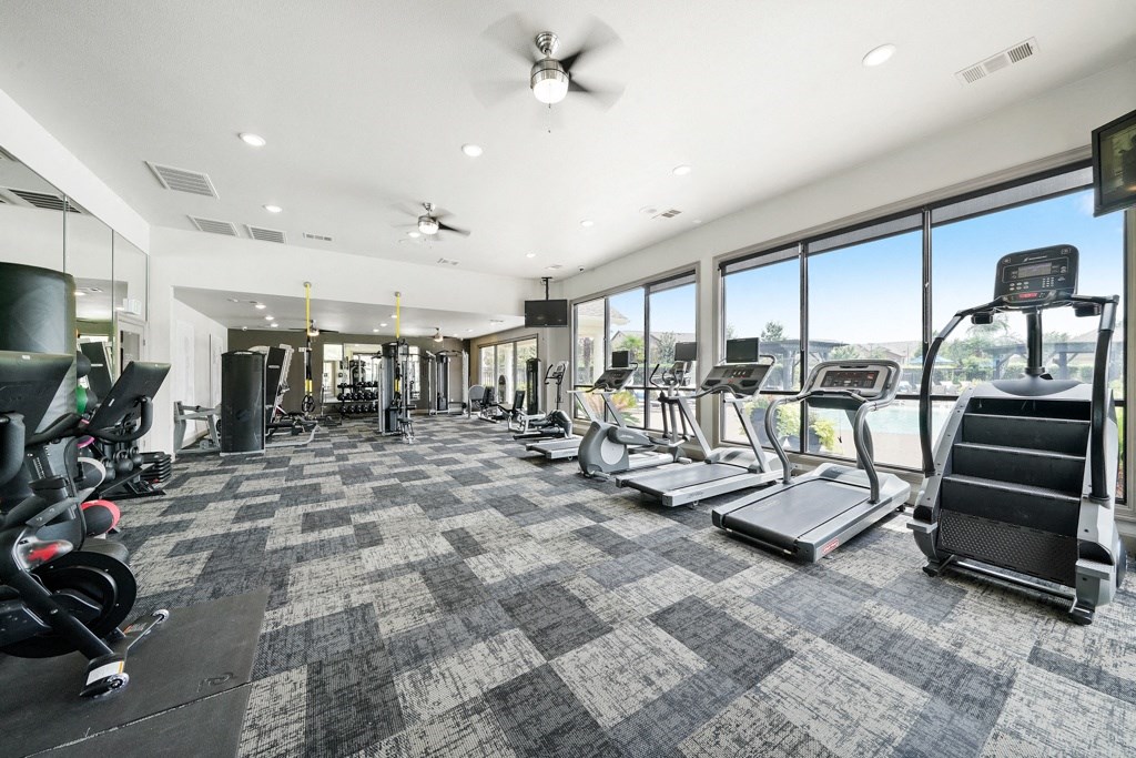 the state of the art fitness room with floor to ceiling windows and cardio equipment at Grand Villas Apartments, Texas, 77494