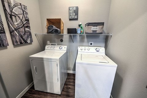 two washers and a dryer in a laundry room with a shelf above them at Waterstone at Cinco Ranch, Katy, Texas