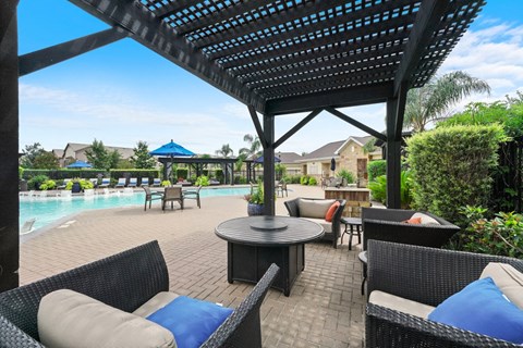 a patio with chairs and a table next to a swimming pool