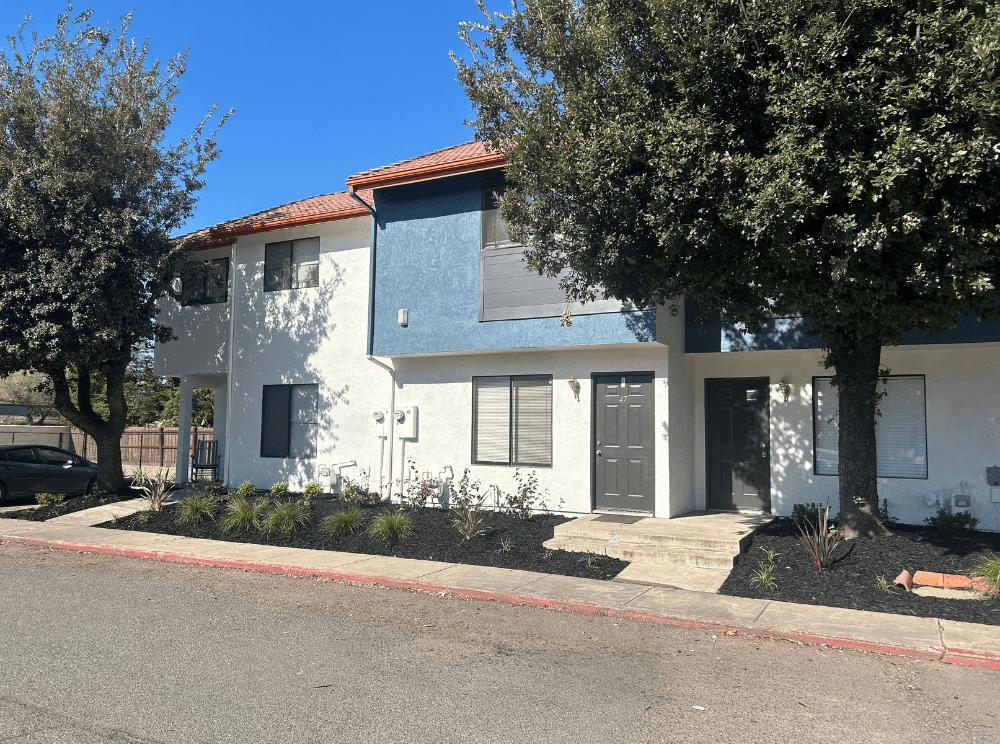 a white and blue house with trees in front of it