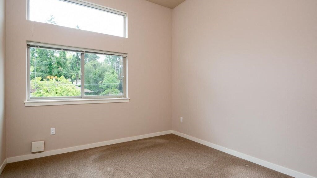 an empty bedroom with a window and carpeting