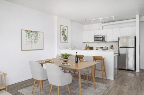 Studio Apartments in Southeast Portland, OR - The Lenox - Dining Area with a 4-Piece Dining Set, Luxury Wood Grain Vinyl Plank Flooring, and White Kitchen