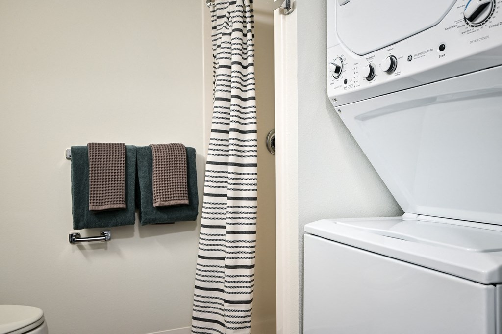 a bathroom with a washer and dryer and a towel rack next to a