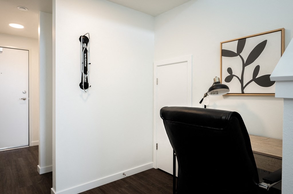 an office space with a black leather chair and a white wall with a bike rack
