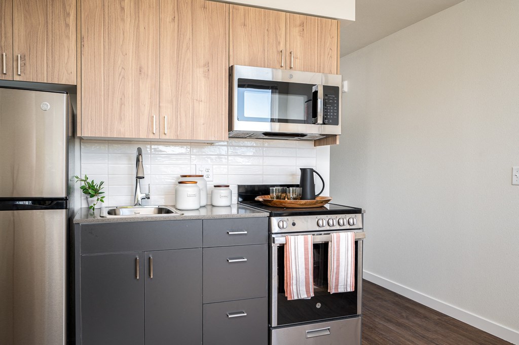 kitchen with stainless steel refrigerator, microwave, stove, and two-tone wood cabinetry