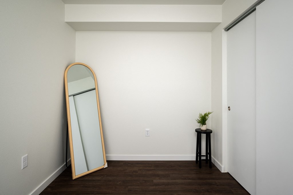 a mirror on a wall in a room with wooden floors and white walls