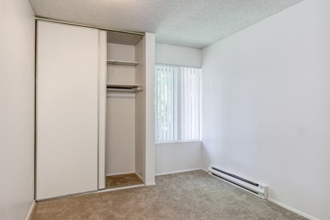 an empty bedroom with a closet and a window