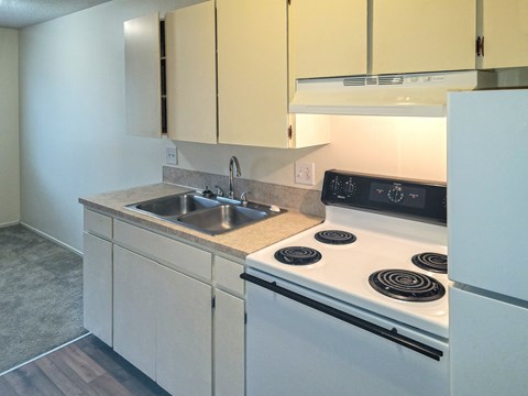 a kitchen with white appliances and white cabinets and a sink