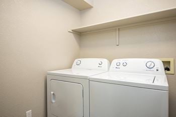 a washer and dryer in a room with a shelf above them