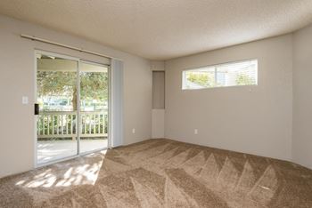 an empty living room with a sliding glass door to a patio