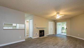 an empty living room with a fireplace and a ceiling fan
