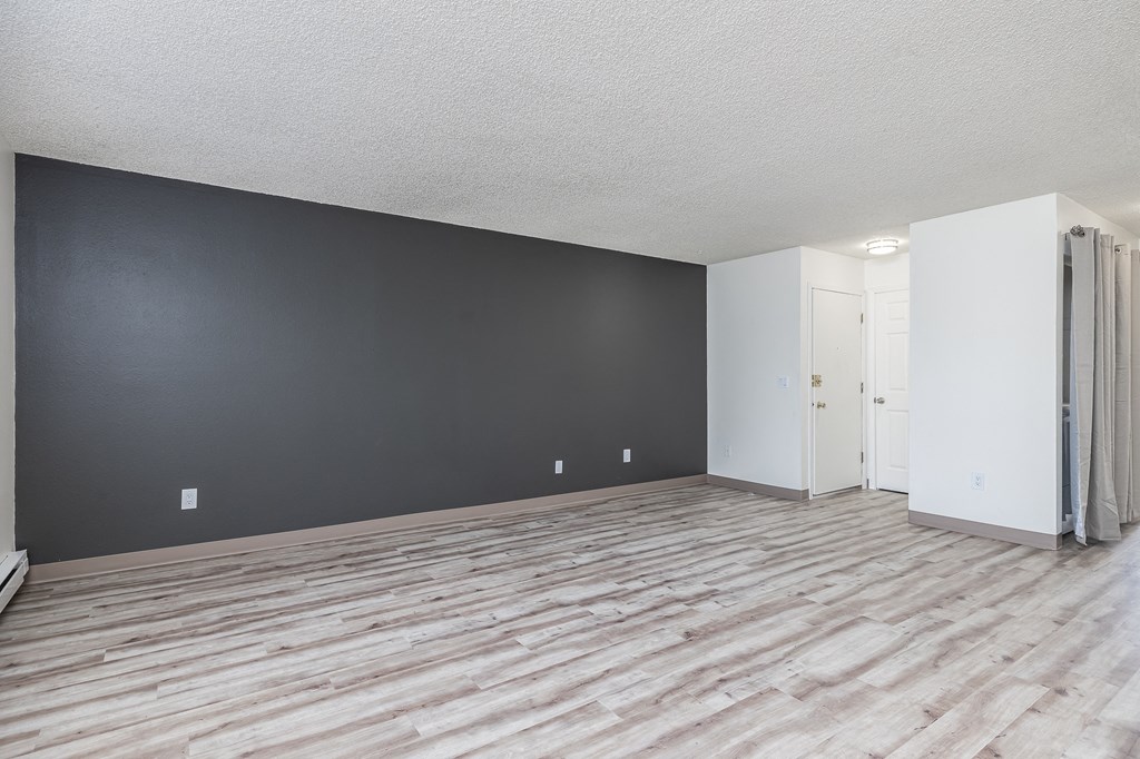 the living room and dining room of an apartment with wood flooring
