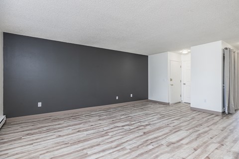 the living room and dining room of an apartment with wood flooring