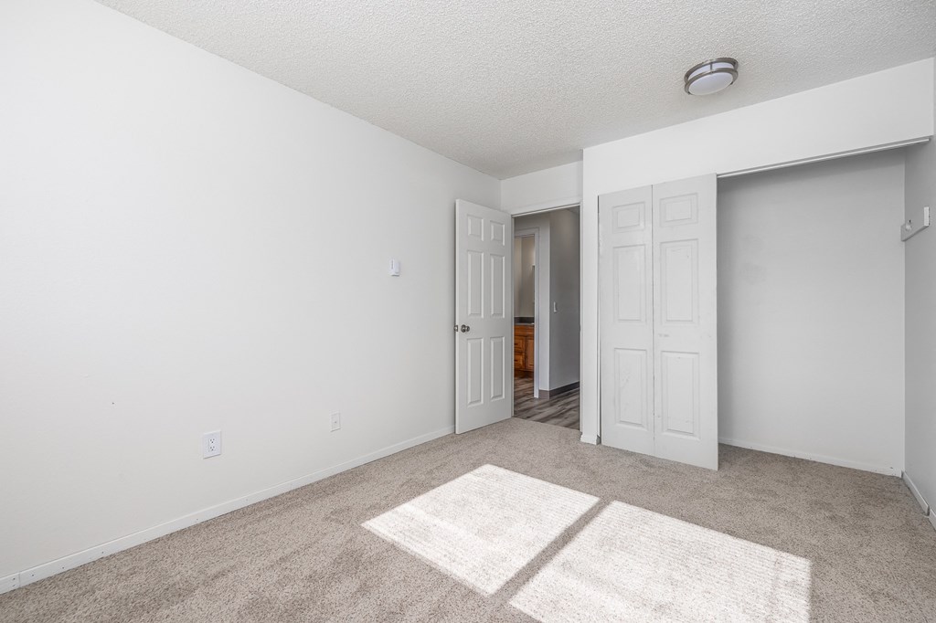 an empty living room with white walls and a door to a hallway