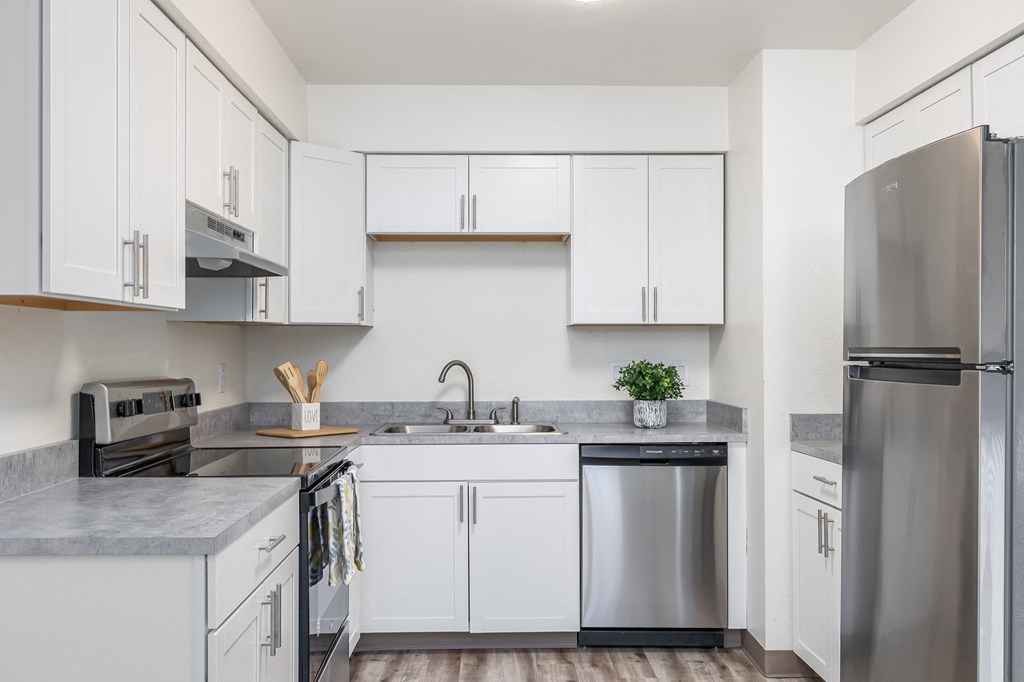 an empty kitchen with white cabinets and stainless steel appliances