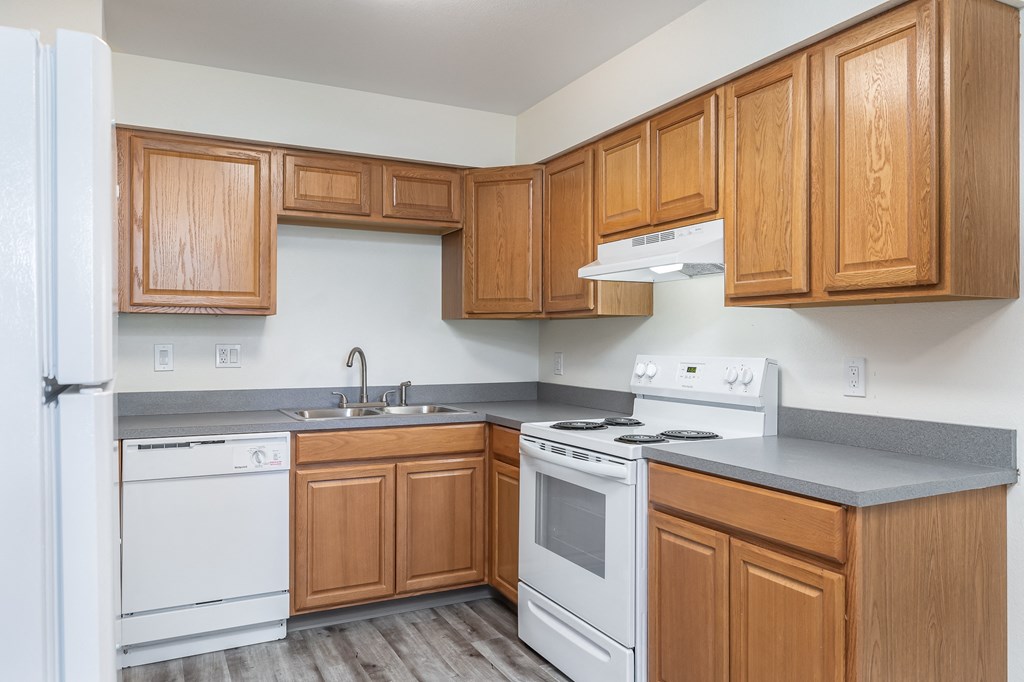 an empty kitchen with white appliances and wooden cabinets