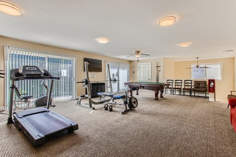 A spacious room with a treadmill, exercise bike, and a table set up for dining.