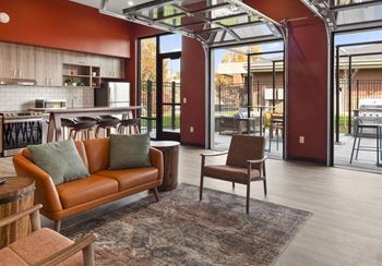 a living room with a couch and chairs and a kitchen